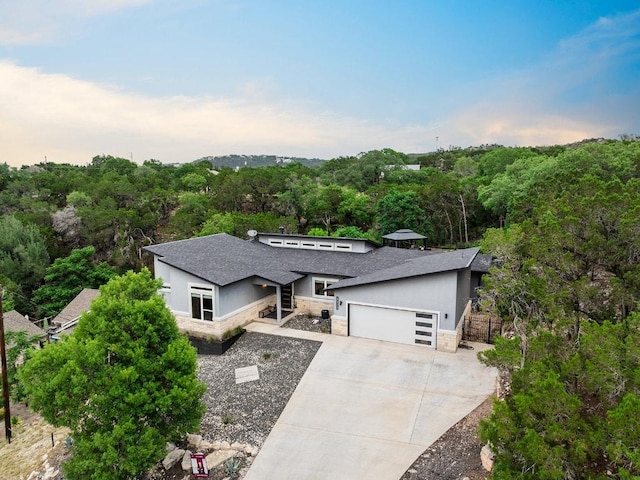 20702 Post Oak Dr, Lago Vista, TX 78645 - view of front of property with stone siding, a garage, stucco siding, a wooded view, and concrete driveway
