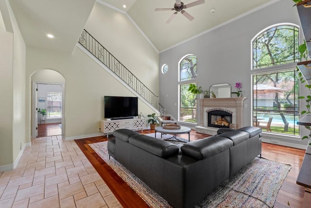 205 Champion Dr, Lakeway, TX 78734 - living area featuring a ceiling fan, arched walkways, a towering ceiling, a fireplace, and ornamental molding