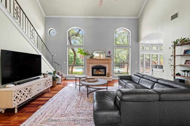 205 Champion Dr, Lakeway, TX 78734 - living room with dark wood finished floors, crown molding, a high ceiling, stairway, and a fireplace with raised hearth