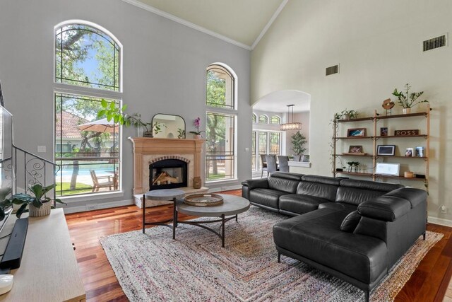 205 Champion Dr, Lakeway, TX 78734 - living area featuring high vaulted ceiling, arched walkways, crown molding, wood finished floors, and a fireplace with raised hearth