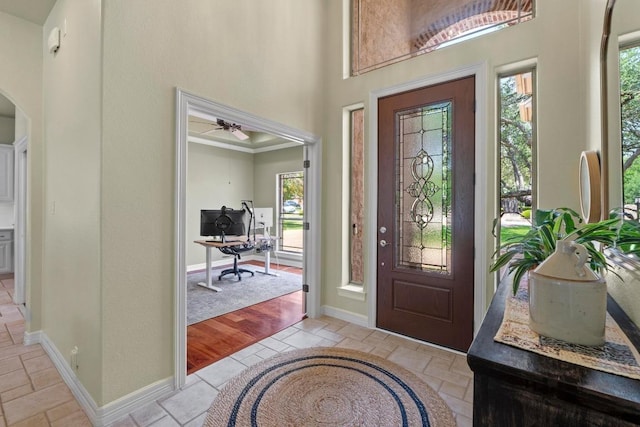 205 Champion Dr, Lakeway, TX 78734 - entryway featuring healthy amount of natural light, a towering ceiling, arched walkways, a ceiling fan, and stone tile flooring