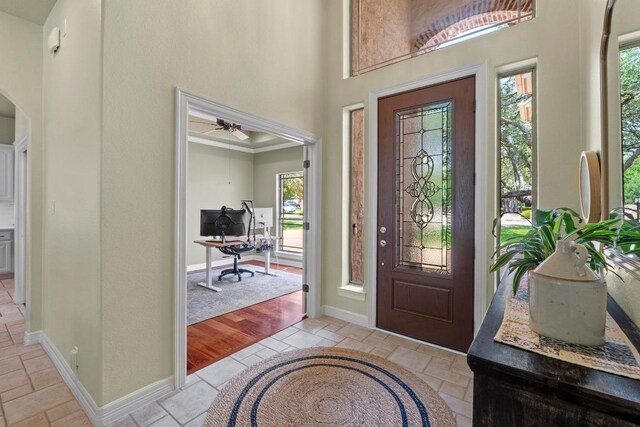 205 Champion Dr, Lakeway, TX 78734 - foyer entrance with healthy amount of natural light, a high ceiling, arched walkways, a ceiling fan, and stone tile floors