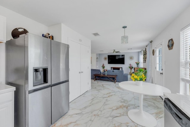 18400 Sun Haven Cv, Elgin, TX 78621 - kitchen with appliances with stainless steel finishes, light marble finish floors, white cabinets, a ceiling fan, and hanging light fixtures