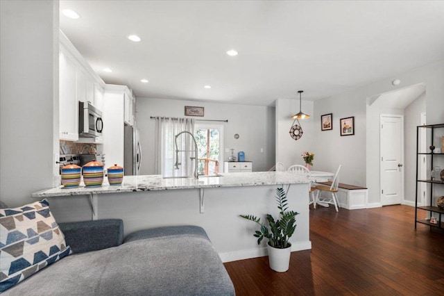 103 Lei Ct, Bastrop, TX 78602 - kitchen featuring stainless steel appliances, white cabinetry, light stone countertops, dark wood-type flooring, and a peninsula