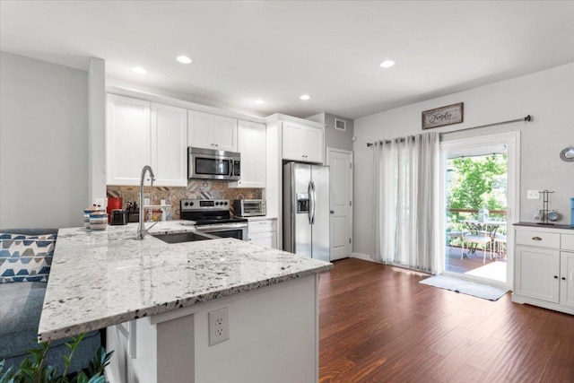 103 Lei Ct, Bastrop, TX 78602 - kitchen with stainless steel appliances, a sink, a peninsula, light stone countertops, and white cabinets