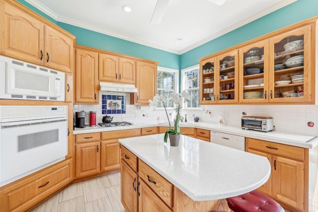 418 Grace Ln, Austin, TX 78746 - kitchen with white appliances, light countertops, under cabinet range hood, glass insert cabinets, and decorative backsplash