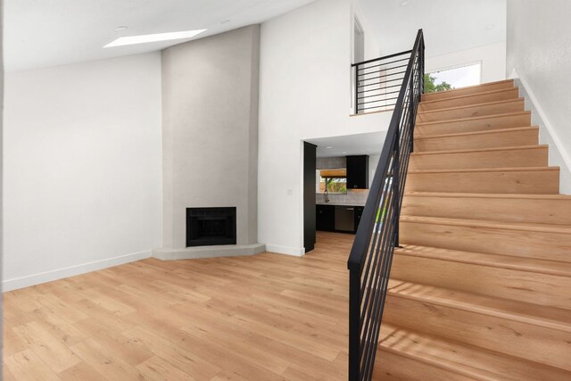 2716 Gettysburg Dr, Austin, TX 78745 - stairway featuring wood finished floors, baseboards, a large fireplace, a skylight, and a high ceiling