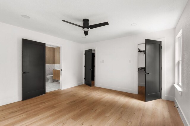 2716 Gettysburg Dr, Austin, TX 78745 - unfurnished bedroom with light wood finished floors, a spacious closet, connected bathroom, baseboards, and a ceiling fan
