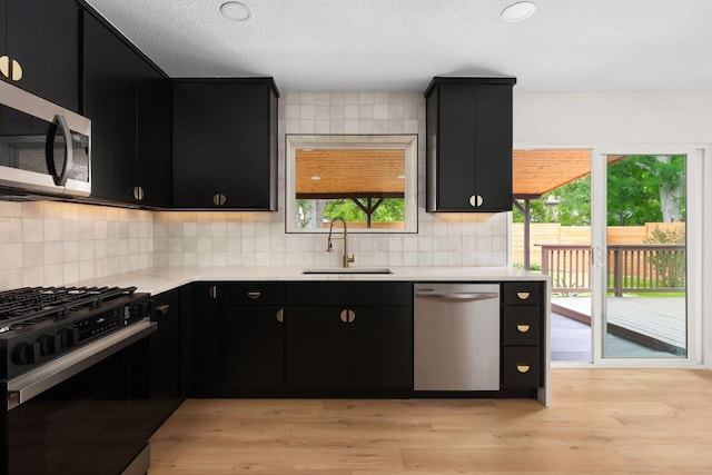 2716 Gettysburg Dr, Austin, TX 78745 - kitchen with stainless steel appliances, dark cabinetry, a sink, light countertops, and a textured ceiling