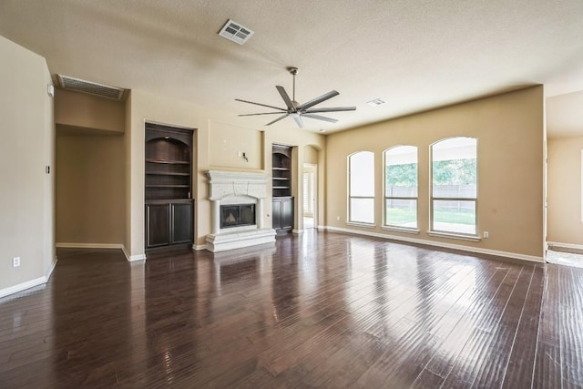 20125 Chayton Cir, Pflugerville, TX 78660 - unfurnished living room with a ceiling fan, built in shelves, wood finished floors, and a glass covered fireplace