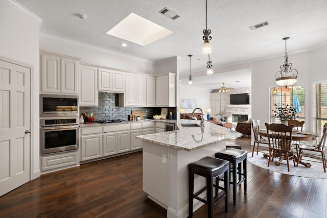 11 Meadow Run, Round Rock, TX 78664 - kitchen featuring stainless steel appliances, a sink, ornamental molding, dark wood-style floors, and a breakfast bar