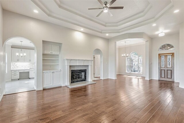 9010 Bluegrass Dr, Austin, TX 78759 - unfurnished living room with a chandelier, a ceiling fan, wood finished floors, a tray ceiling, and a fireplace