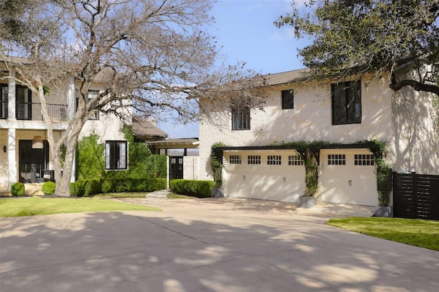 102 Crestwood Ct, Austin, TX 78746 - view of front of house with driveway, an attached garage, stucco siding, and a balcony