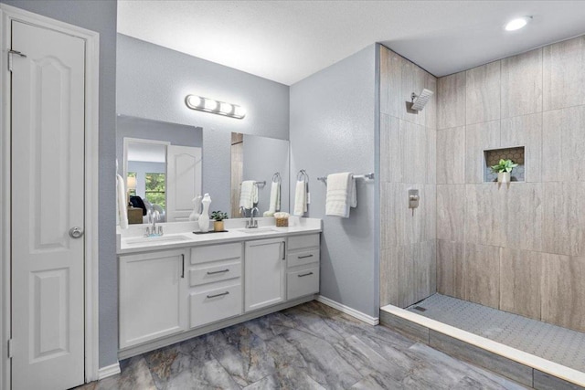 1222 Minerva St, Austin, TX 78753 - bathroom featuring walk in shower, marble finish flooring, double vanity, a textured wall, and baseboards