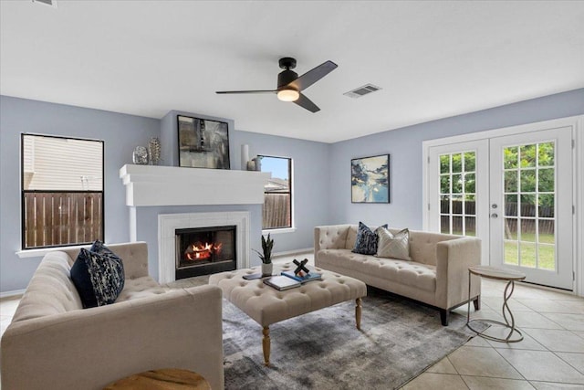 1222 Minerva St, Austin, TX 78753 - living room with ceiling fan, a lit fireplace, light tile patterned flooring, and french doors