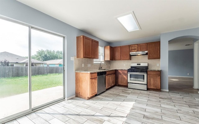 3907 Sojourner St, Austin, TX 78725 - kitchen featuring stainless steel appliances, under cabinet range hood, decorative backsplash, and arched walkways