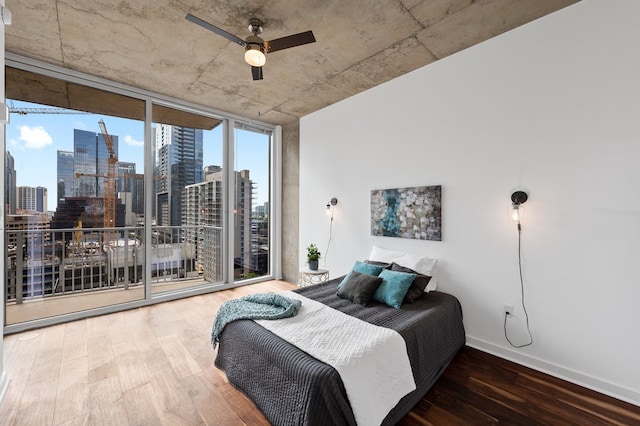 360 Nueces St Unit 1407, Austin, TX 78701 - bedroom featuring wood finished floors, a skyline view, baseboards, expansive windows, and a ceiling fan