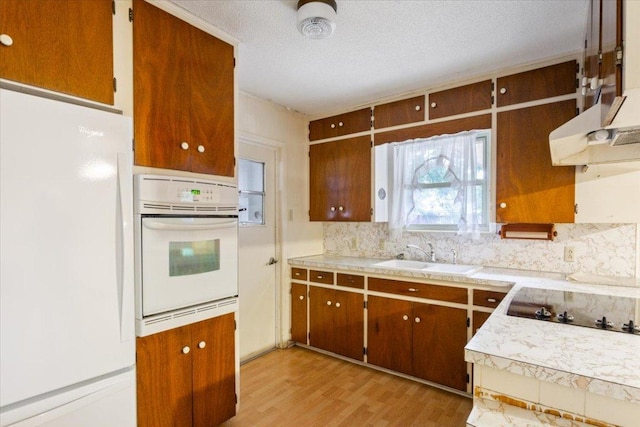 4412 Briar Cliff Rd, Temple, TX 76502 - kitchen with white appliances, a sink, backsplash, light wood finished floors, and light countertops