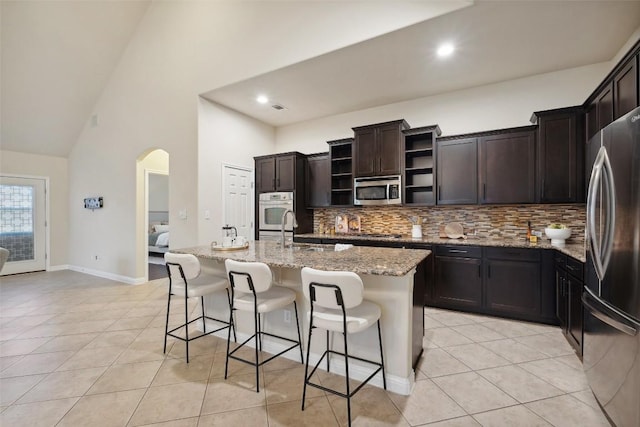 2944 Castellan Ln, Round Rock, TX 78665 - kitchen featuring stainless steel appliances, light tile patterned floors, backsplash, open shelves, and high vaulted ceiling