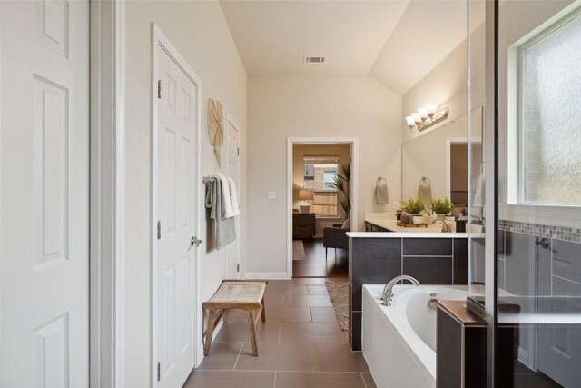 2944 Castellan Ln, Round Rock, TX 78665 - ensuite bathroom featuring a garden tub, tile patterned flooring, vanity, and lofted ceiling