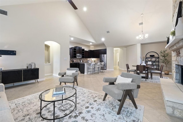 2944 Castellan Ln, Round Rock, TX 78665 - living area featuring light tile patterned flooring, high vaulted ceiling, arched walkways, a chandelier, and a tiled fireplace