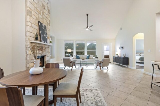 2944 Castellan Ln, Round Rock, TX 78665 - dining area featuring high vaulted ceiling, ceiling fan, a stone fireplace, light tile patterned floors, and arched walkways