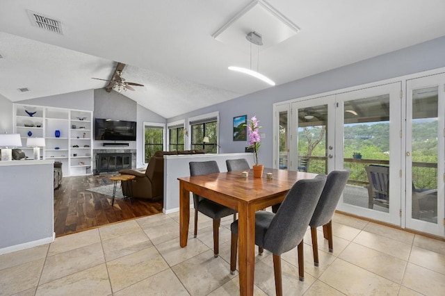 2009 S Oak Canyon Rd, Austin, TX 78746 - dining room featuring french doors, ceiling fan, light tile patterned flooring, and a fireplace