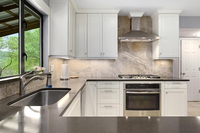 2009 S Oak Canyon Rd, Austin, TX 78746 - kitchen with stainless steel appliances, wall chimney exhaust hood, a sink, decorative backsplash, and white cabinets