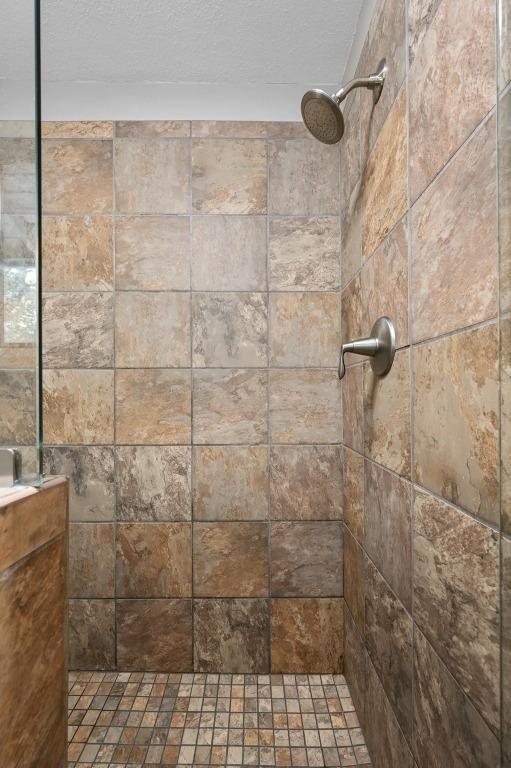 2009 S Oak Canyon Rd, Austin, TX 78746 - bathroom with tiled shower and a textured ceiling