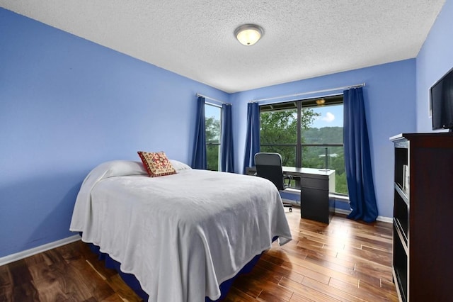 2009 S Oak Canyon Rd, Austin, TX 78746 - bedroom featuring wood finished floors, a textured ceiling, and baseboards