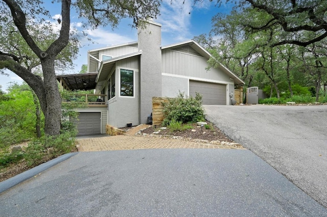 2009 S Oak Canyon Rd, Austin, TX 78746 - view of property exterior with asphalt driveway, a chimney, a balcony, and an attached garage
