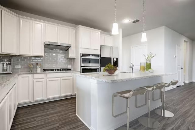 13505 Cerro Castellan Trce, Manor, TX 78653 - kitchen with fridge with ice dispenser, under cabinet range hood, double oven, and dark wood finished floors