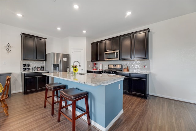 109 Red Cedar Ct, Georgetown, TX 78628 - kitchen featuring appliances with stainless steel finishes, a sink, dark wood-style floors, backsplash, and a breakfast bar