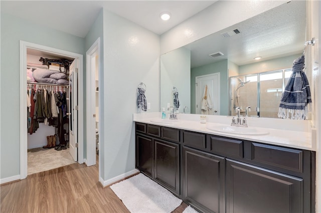 109 Red Cedar Ct, Georgetown, TX 78628 - full bathroom with wood finished floors, double vanity, a stall shower, a walk in closet, and baseboards