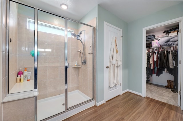 109 Red Cedar Ct, Georgetown, TX 78628 - bathroom with wood finished floors, a stall shower, a spacious closet, and baseboards
