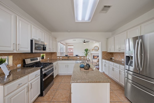 3619 Fossilwood Way, Round Rock, TX 78681 - kitchen with appliances with stainless steel finishes, a sink, a kitchen island, arched walkways, and a ceiling fan