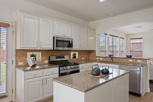 3619 Fossilwood Way, Round Rock, TX 78681 - kitchen with appliances with stainless steel finishes, a peninsula, arched walkways, a kitchen island, and backsplash
