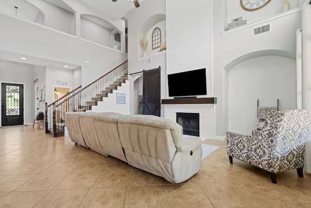 2516 Rusty Spur, Leander, TX 78641 - living room with a high ceiling, light tile patterned floors, stairway, a large fireplace, and a ceiling fan