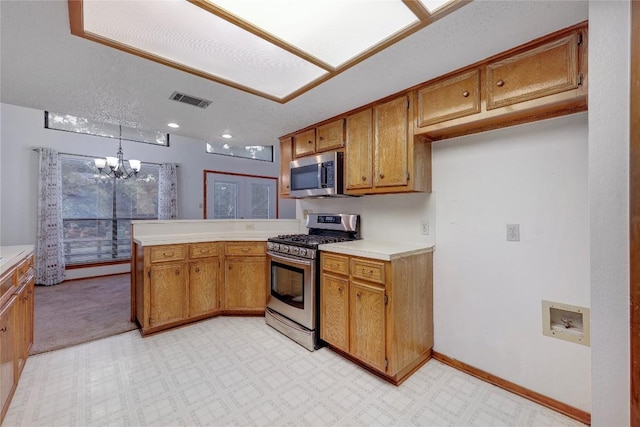 612 Tumlinson Fort Dr, Leander, TX 78641 - kitchen featuring stainless steel appliances, a peninsula, a chandelier, and brown cabinetry