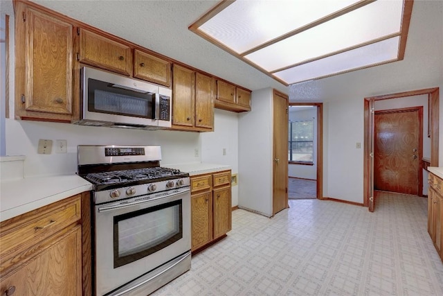 612 Tumlinson Fort Dr, Leander, TX 78641 - kitchen with stainless steel appliances, brown cabinets, light countertops, light flooring, and baseboards