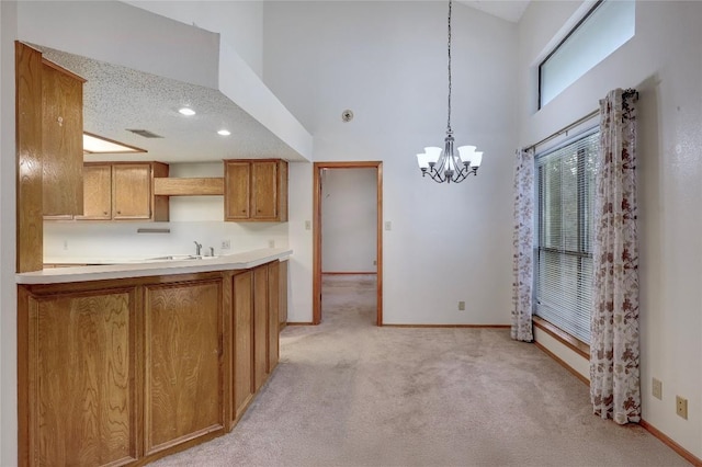 612 Tumlinson Fort Dr, Leander, TX 78641 - kitchen with a high ceiling, a chandelier, baseboards, light colored carpet, and brown cabinetry