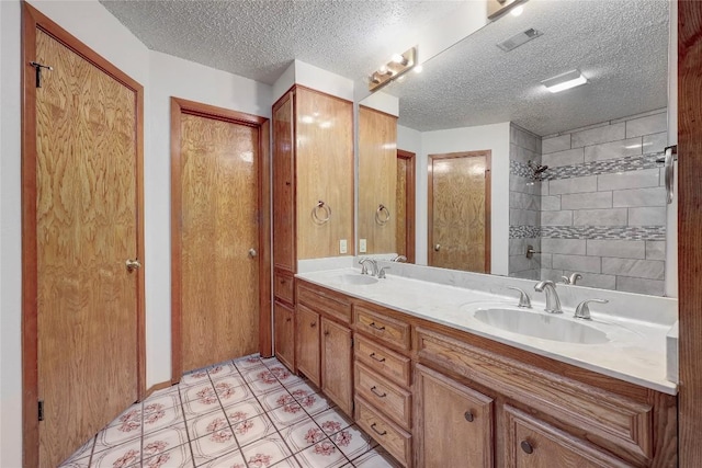 612 Tumlinson Fort Dr, Leander, TX 78641 - bathroom with double vanity, a textured ceiling, a tile shower, and tile patterned flooring