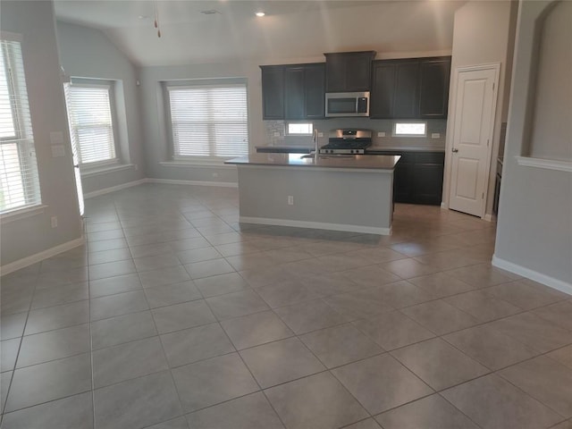 3332 Lauren Nicole Ln, Round Rock, TX 78665 - kitchen featuring stainless steel microwave, light tile patterned floors, lofted ceiling, a kitchen island with sink, and stove