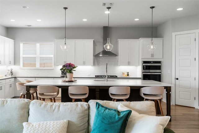 8112 Silhouette St, Austin, TX 78744 - kitchen featuring wall chimney exhaust hood, a kitchen bar, appliances with stainless steel finishes, open floor plan, and backsplash