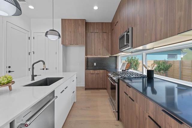 2114 Haskell St, Austin, TX 78702 - kitchen featuring modern cabinets, appliances with stainless steel finishes, brown cabinetry, light wood finished floors, and backsplash