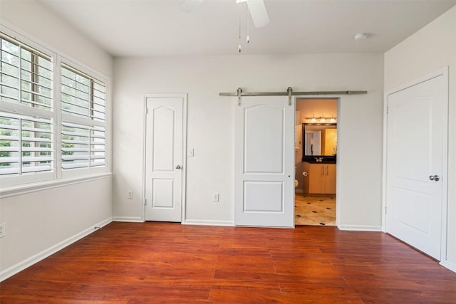 11203 Ranch Road 2222 1501, Austin, TX 78730 - unfurnished bedroom with wood finished floors, a barn door, baseboards, and ensuite bathroom