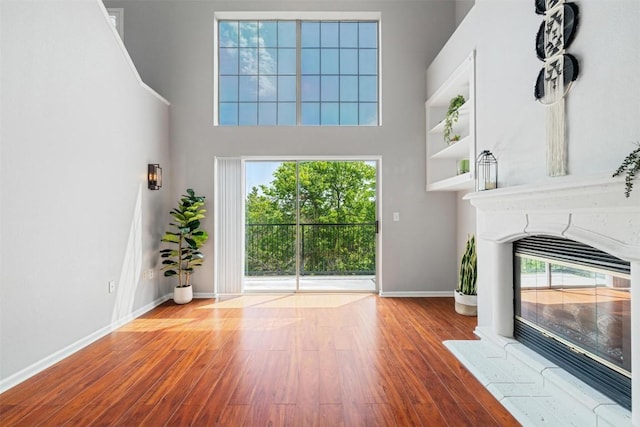 11203 Ranch Road 2222 1501, Austin, TX 78730 - unfurnished living room with a fireplace with flush hearth, wood finished floors, baseboards, and a high ceiling