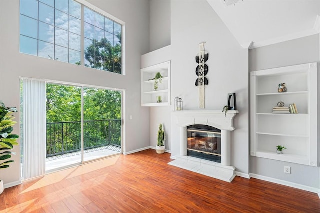 11203 Ranch Road 2222 1501, Austin, TX 78730 - unfurnished living room with a high ceiling, a glass covered fireplace, wood finished floors, and baseboards