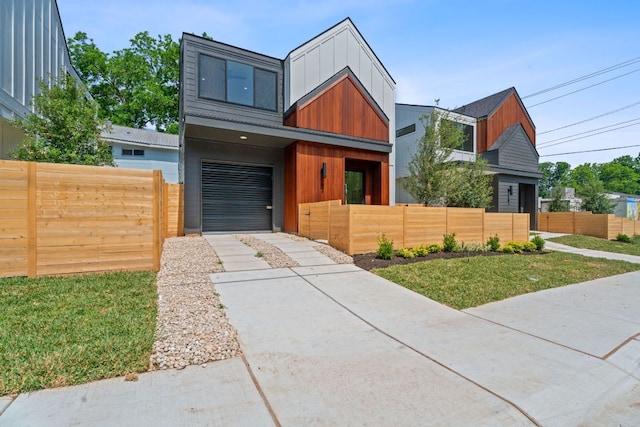 52 Robert T Martinez Jr St, Austin, TX 78702 - modern home featuring concrete driveway, a fenced front yard, an attached garage, and board and batten siding