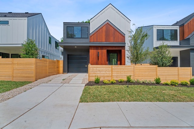 52 Robert T Martinez Jr St, Austin, TX 78702 - contemporary home with driveway, a fenced front yard, a garage, and board and batten siding